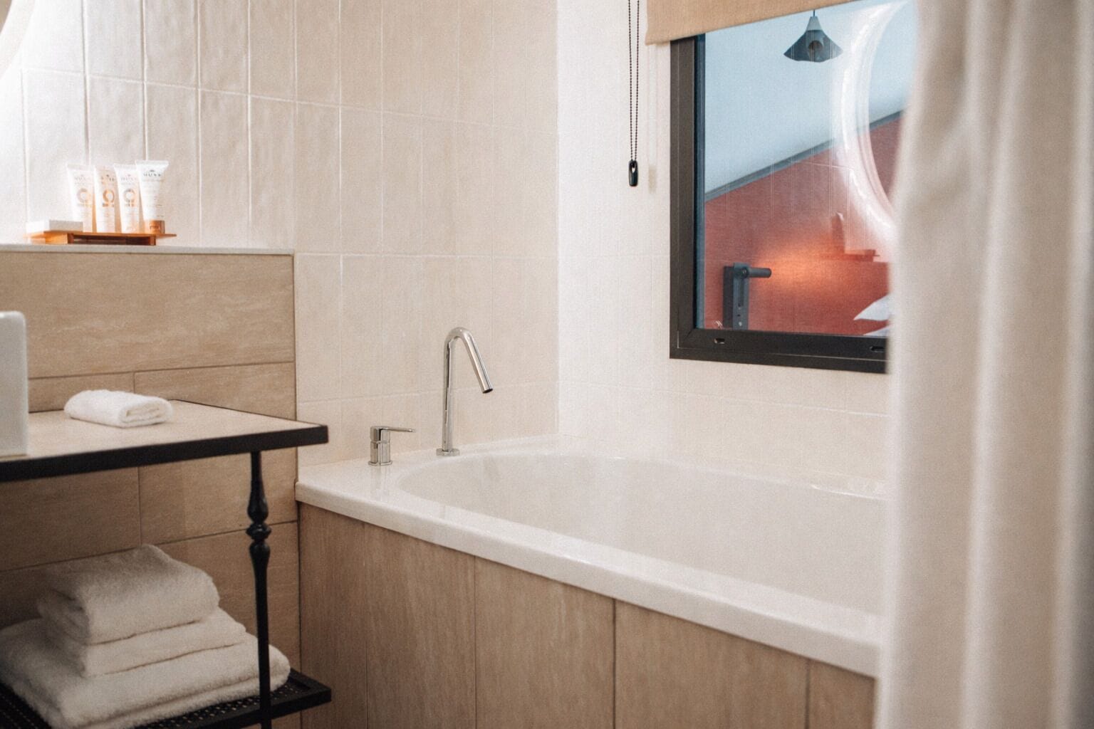 A modern bathroom with a freestanding bathtub, a vanity with a towel rack, and a window with a view of a building.