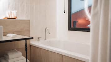 A modern bathroom with a freestanding bathtub, a vanity with a towel rack, and a window with a view of a building.