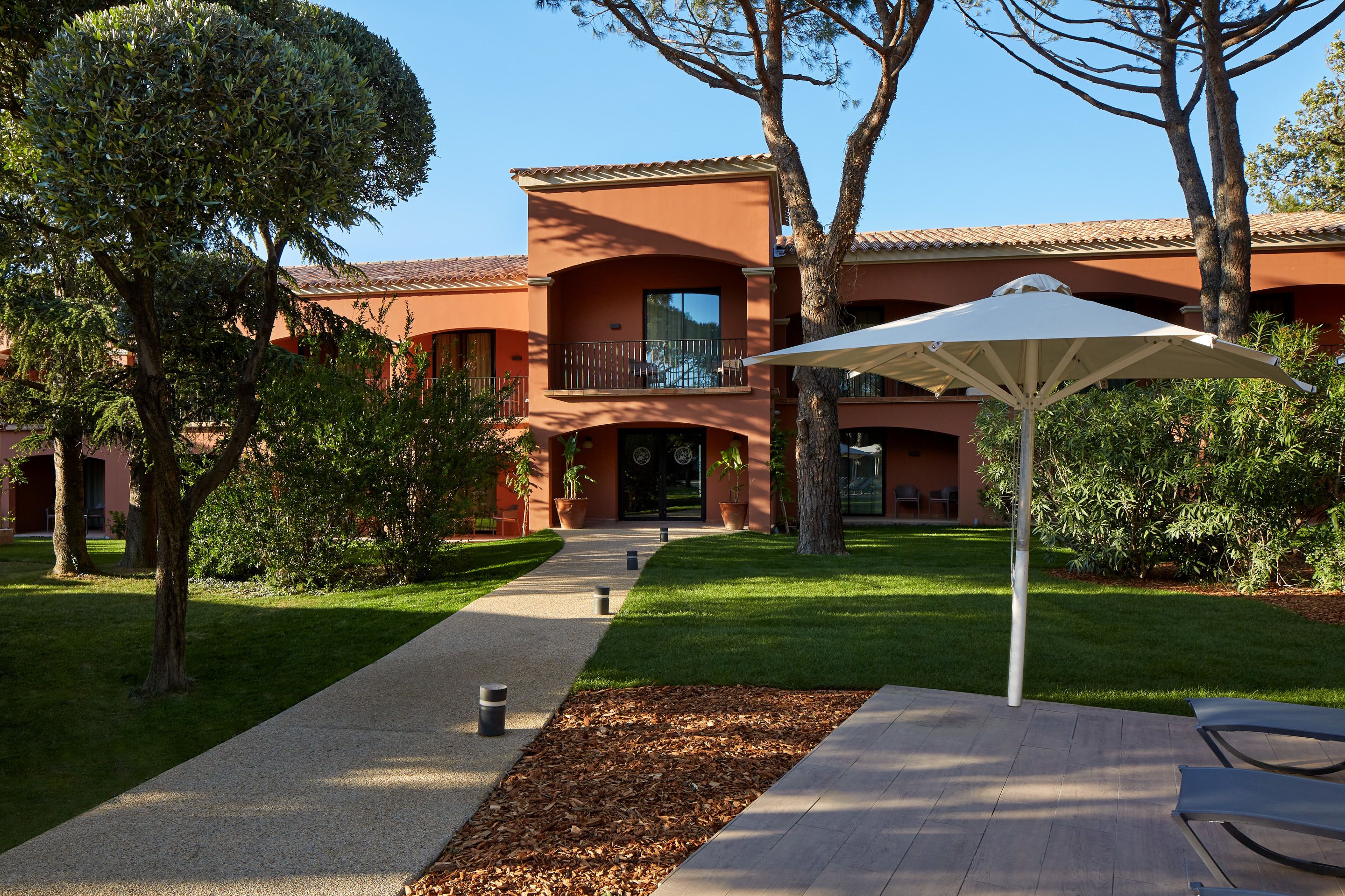 A courtyard with a pathway leading to a building with a balcony.