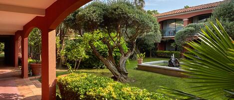 A courtyard with a fountain, well-maintained hedges, and a building with a tiled roof.