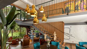 A spacious living area with a staircase, a large potted plant, and a bookshelf.