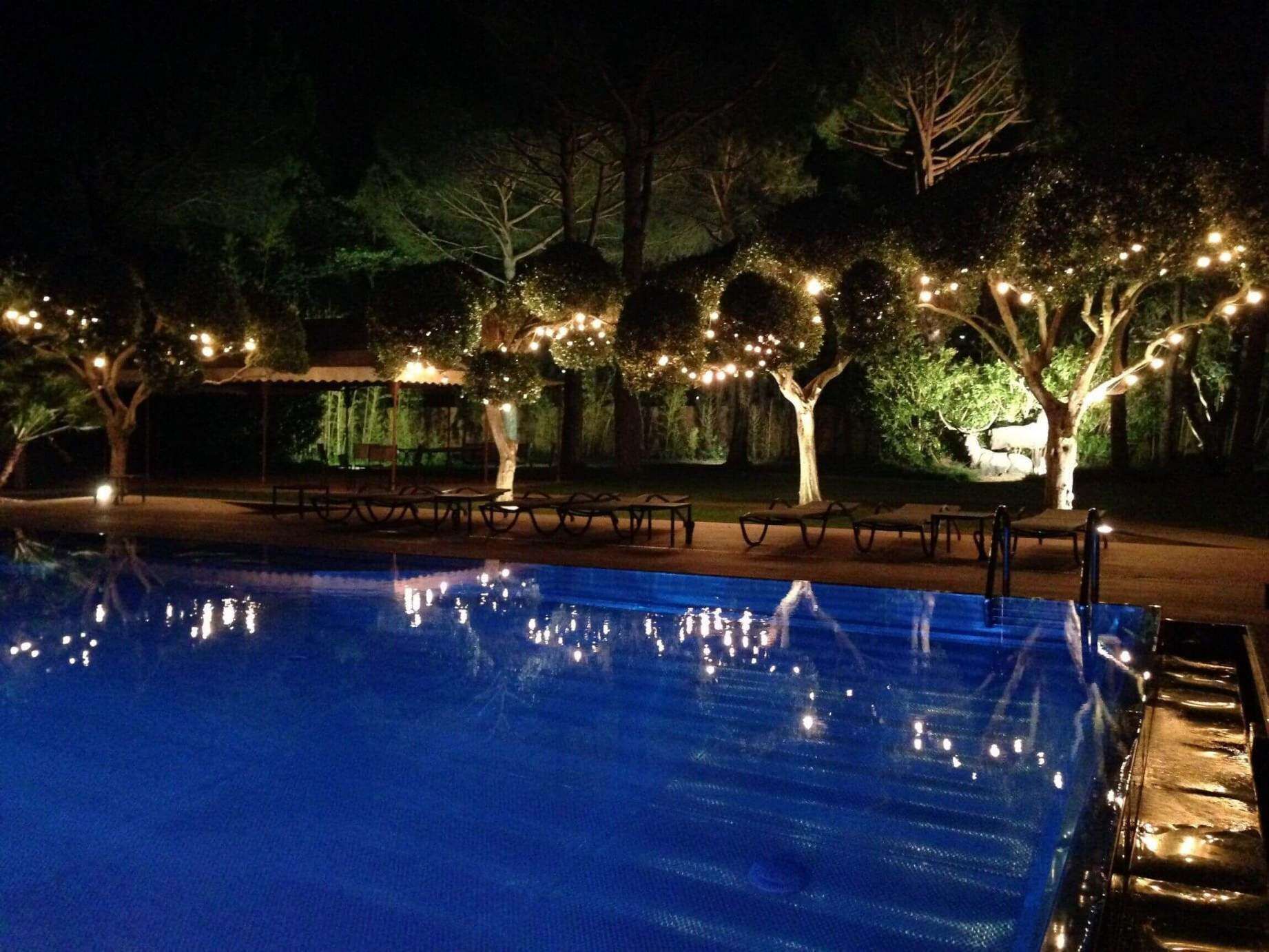 Piscina rodeada de árboles y bancos.