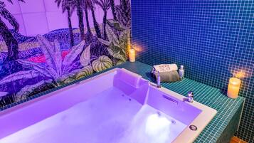 A modern bathroom with a large bathtub, a tropical mural, and a blue tiled wall.