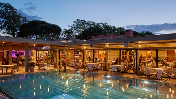 An indoor swimming pool with adjacent dining areas and a bar.