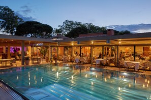 An indoor swimming pool with adjacent dining areas and a bar.