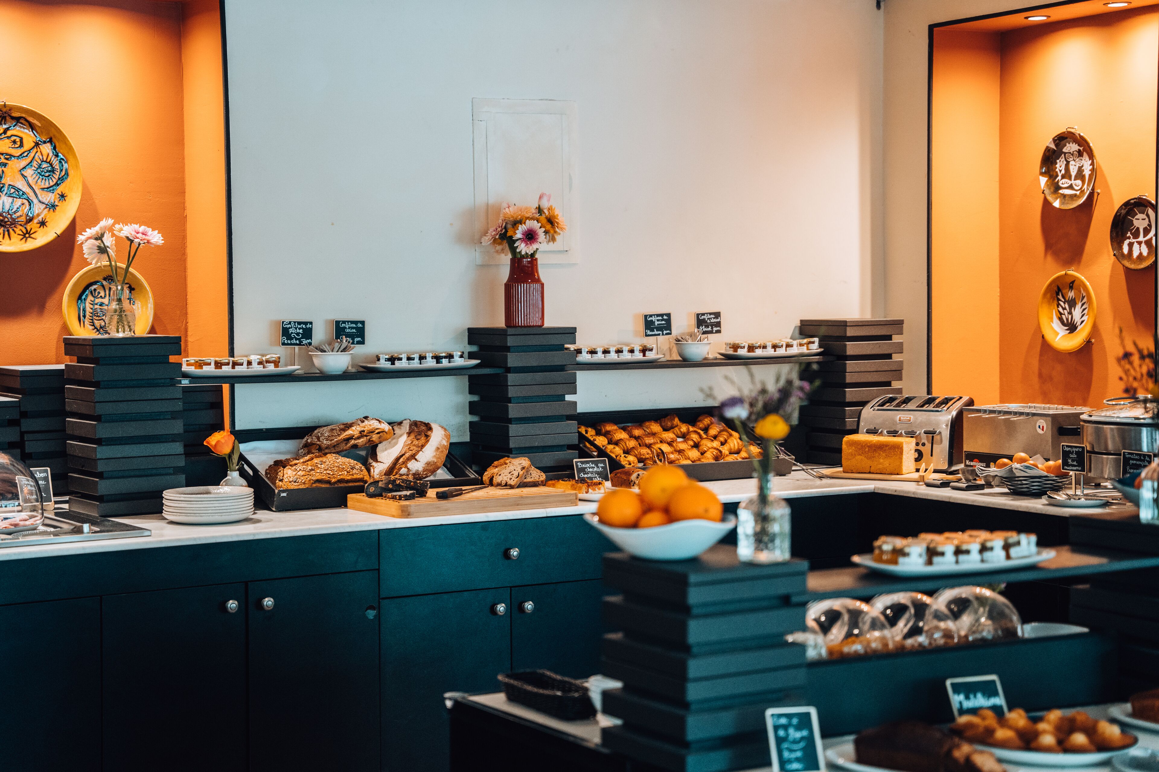 Un bufé con diversas opciones de comida, entre ellas pastelería, frutas y una estación de café.