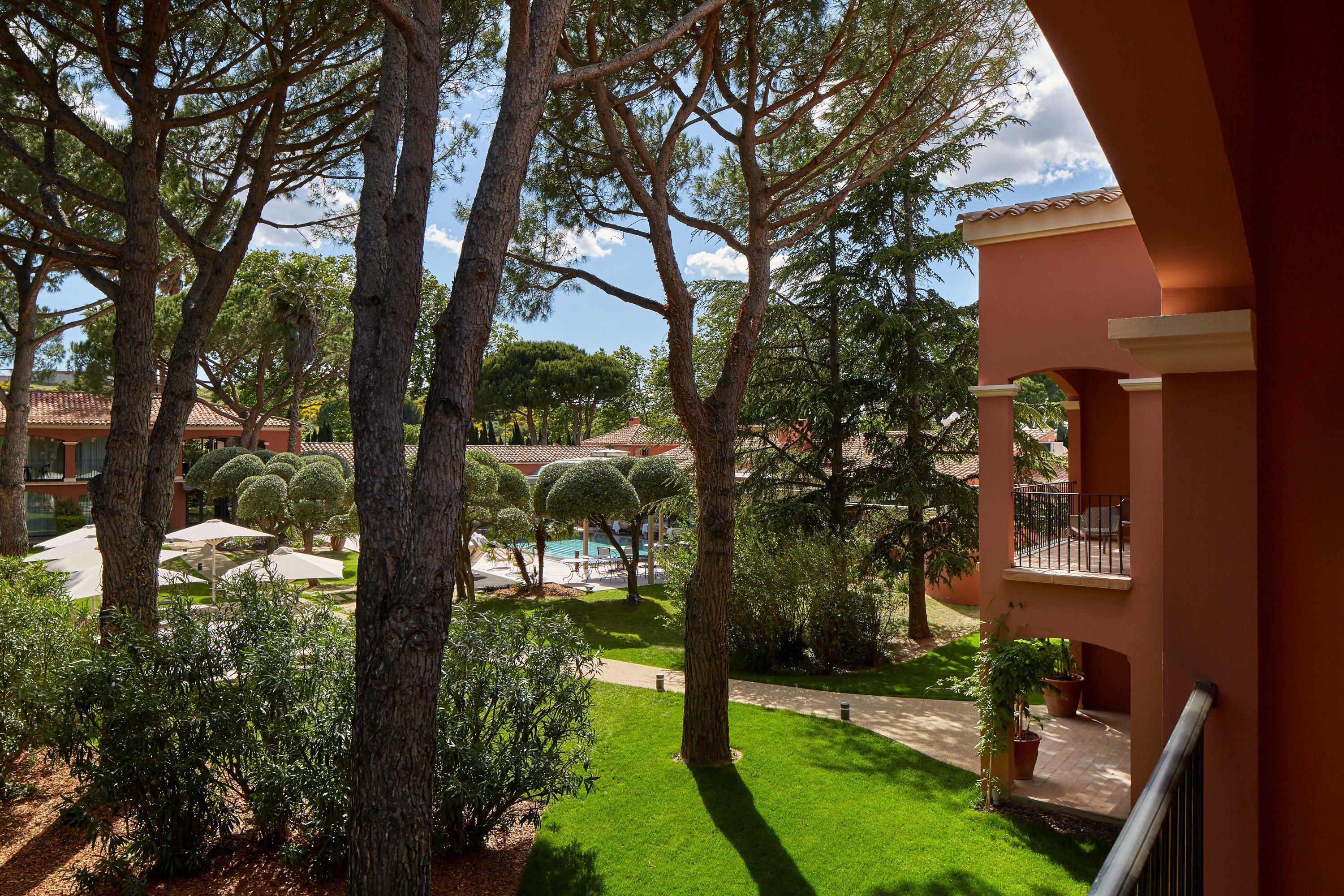 A courtyard with a swimming pool, surrounded by trees and a building with balconies.