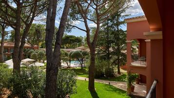 A courtyard with a swimming pool, surrounded by trees and a building with balconies.