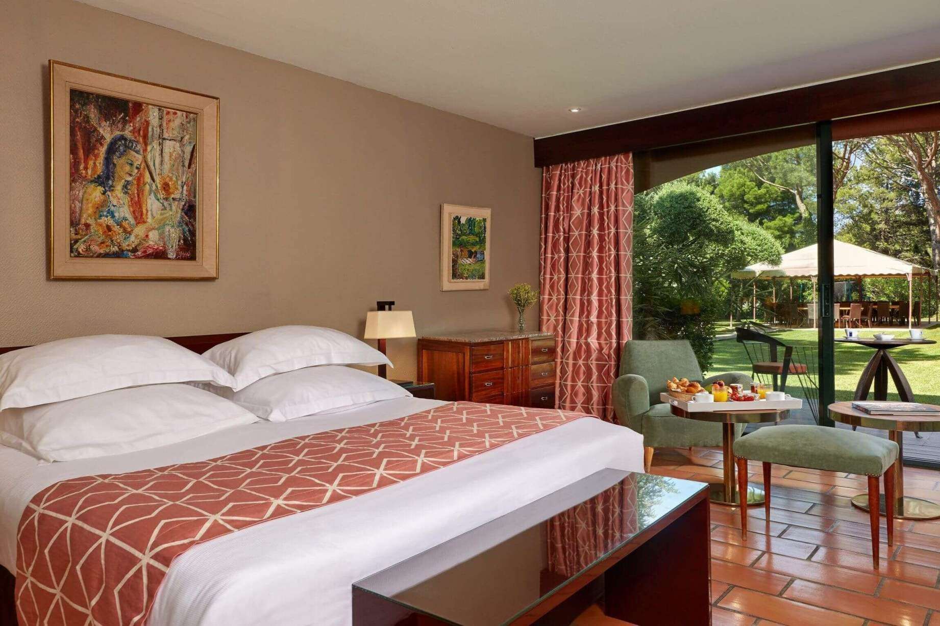 A hotel room with a bed, a desk, a chair, and a view of the outdoors.