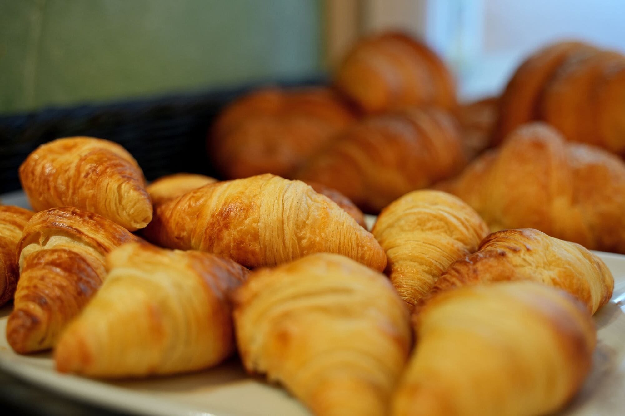 Lautasella on erilaisia leivonnaisia, kuten croissantteja ja muita uunissa paistettuja herkkuja.