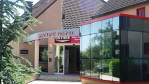 The exterior of Mercure Hotel with a modern glass entrance and a sign indicating an entrance. - Mercure Luxeuil les Bains Hexagone (Luxeuil-les-Bains)