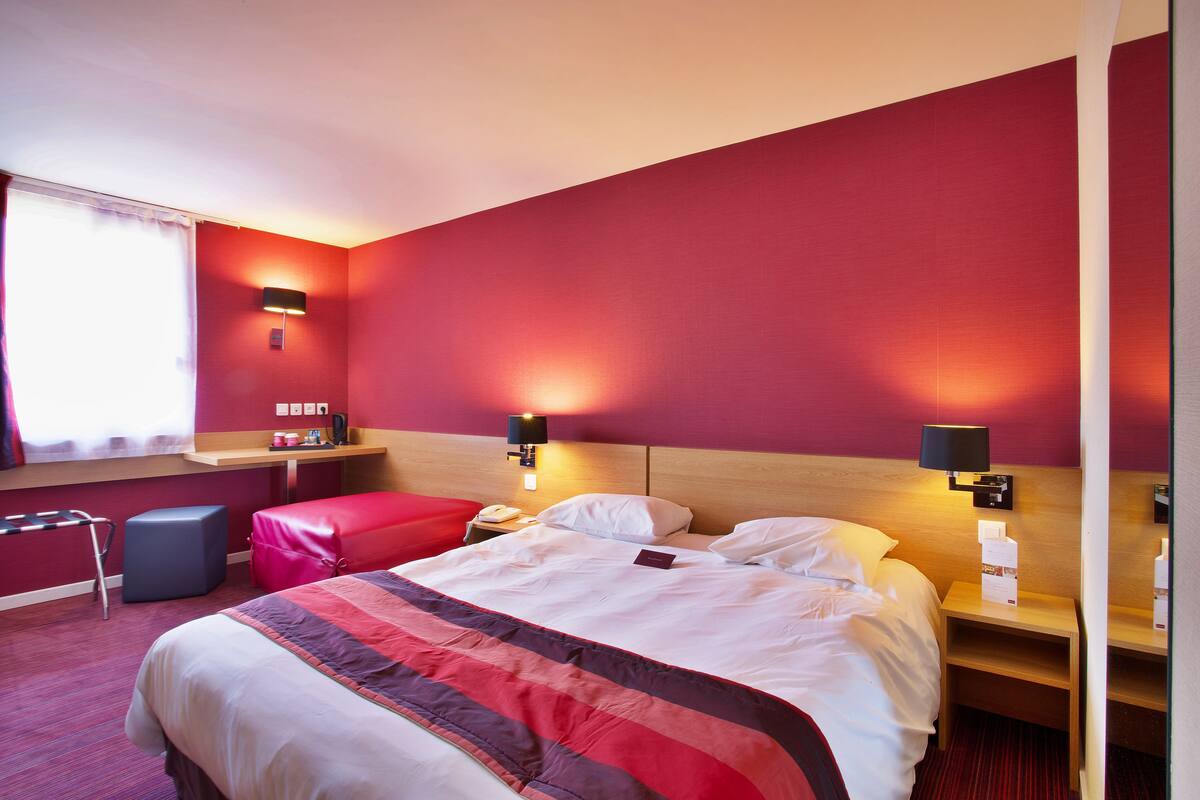 A hotel room with a large bed, two bedside tables, a desk, and a chair.