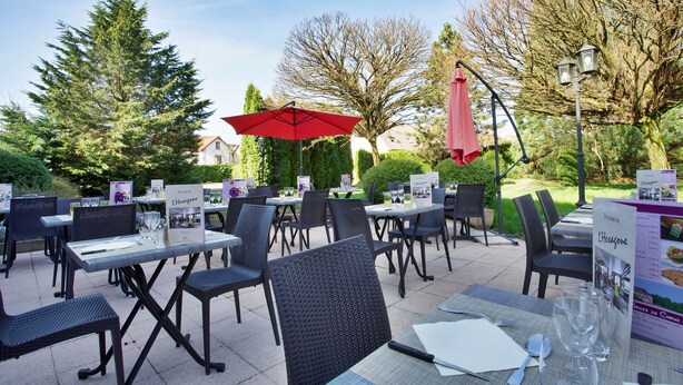An outdoor dining area with tables and chairs, surrounded by trees and a clear sky. - Mercure Luxeuil les Bains Hexagone (Luxeuil-les-Bains)