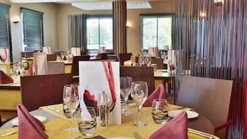 Un restaurante con mesas dispuestas para comer, incluyendo copas de vino, platos y cubiertos.