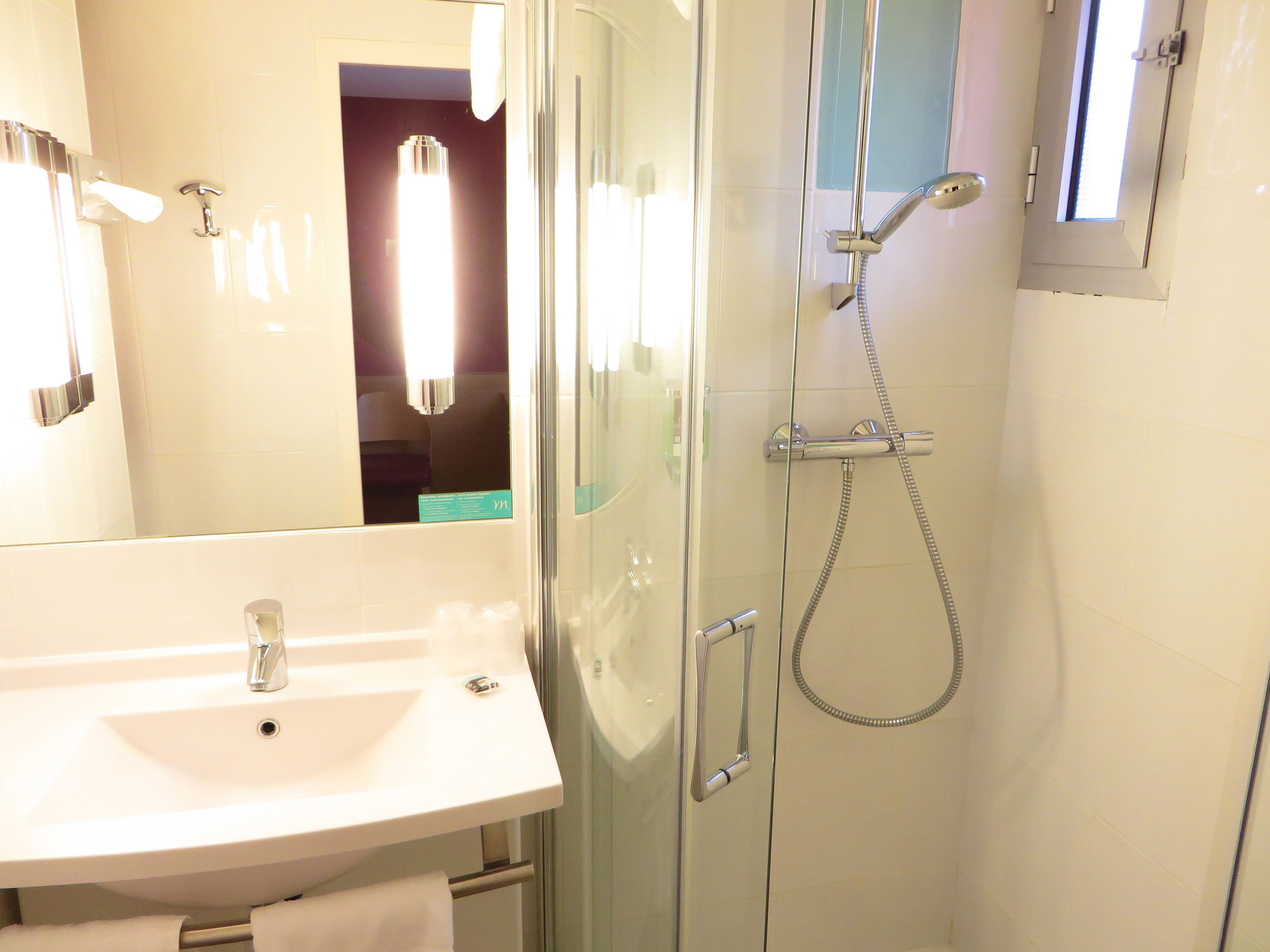 A bathroom with a glass-enclosed shower, a white sink, and a mirror.