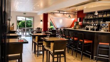 A restaurant interior with tables and chairs, a bar area with bottles and a cash register, and a sign indicating a brasserie.