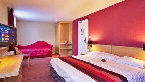 A hotel room with a bed, a desk, a TV, a red sofa, and a wooden wardrobe. - Mercure Luxeuil les Bains Hexagone (Luxeuil-les-Bains)