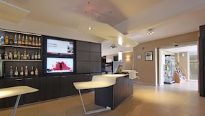 A modern reception area with a bar, seating, and a digital display. - Mercure Luxeuil les Bains Hexagone (Luxeuil-les-Bains)