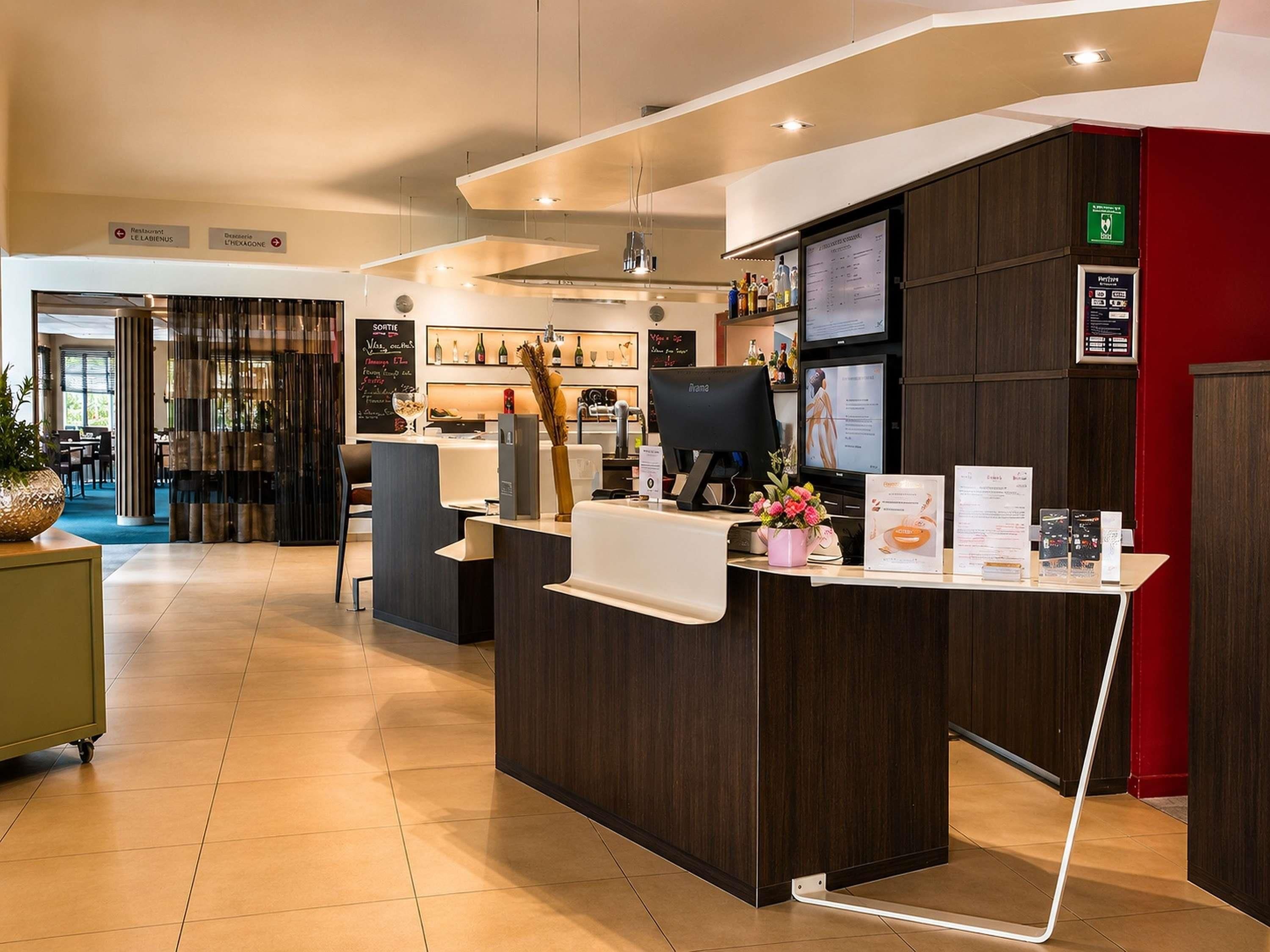 A hotel reception area with a reception desk, a computer, and a menu board.