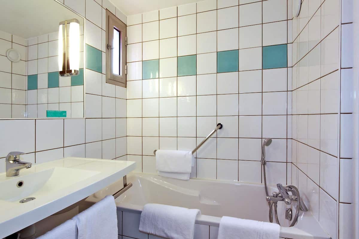A bathroom with a white sink, mirror, and bathtub.