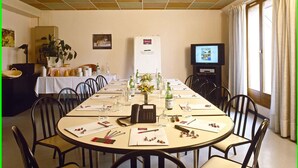 A conference room with a long table, chairs, a projector screen, and a television. - Mercure Luxeuil les Bains Hexagone (Luxeuil-les-Bains)