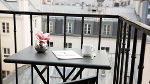 Un balcon avec une petite table, une tasse blanche, une cuillère et un vase à fleurs.