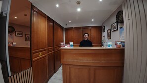 Una reception con pannelli in legno, una sveglia, quadri incorniciati e brochure informative.