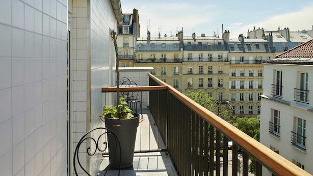 A balcony with a potted plant, a railing, and a view of adjacent buildings. - Hôtel Darcet Paris (Paris)