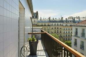 A balcony with a potted plant, a railing, and a view of adjacent buildings. - Hôtel Darcet Paris (Paris)