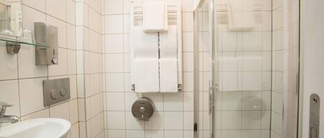 Un baño con cabina de ducha de vidrio, lavabo e inodoro.