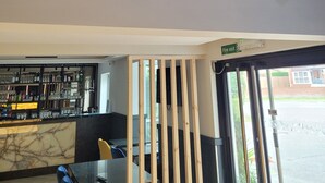 L’intérieur d’un restaurant, avec un bar, un espace réservé aux clients et un panneau indiquant clairement la sortie de secours.