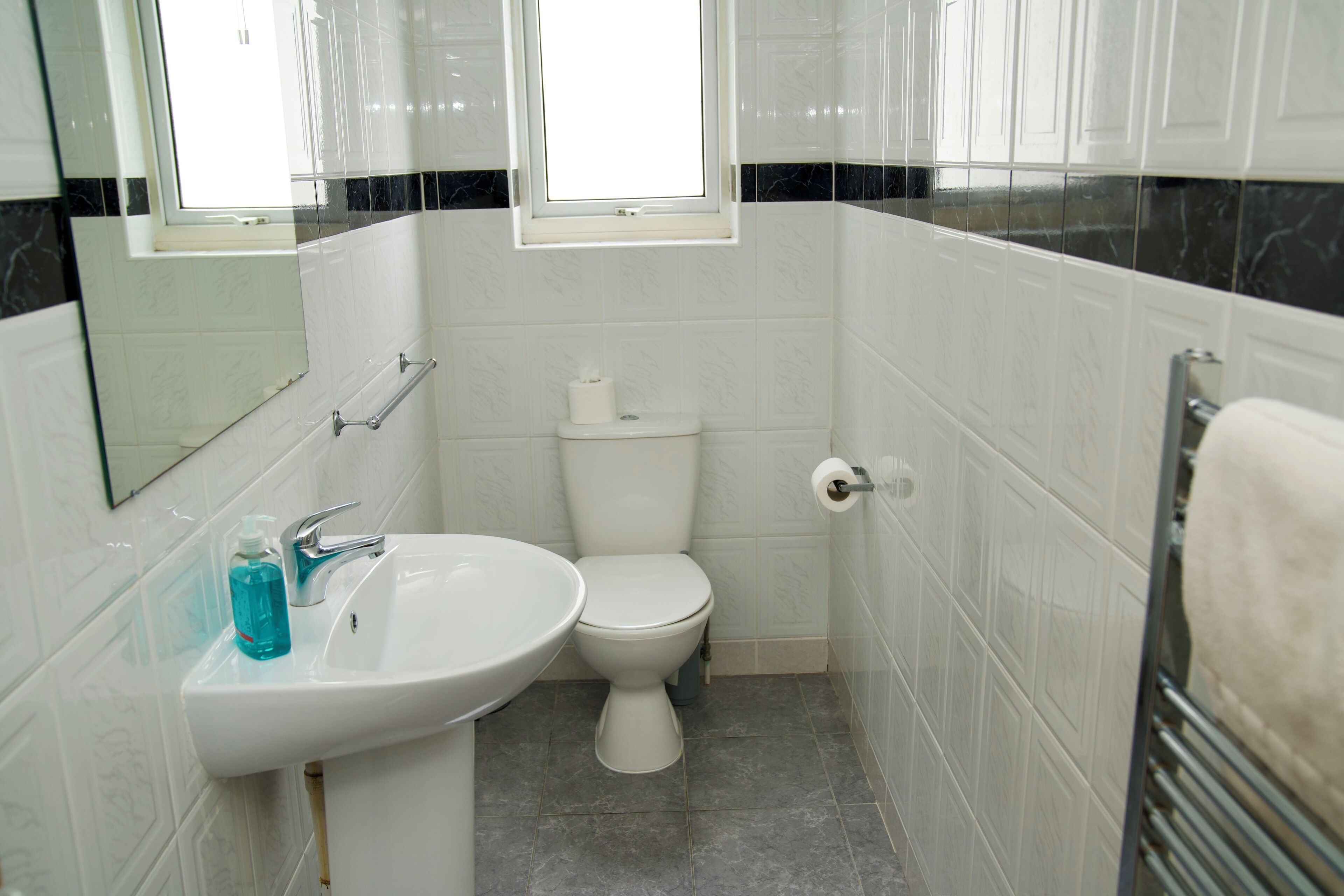 A bathroom with a white sink, toilet, and a window above the toilet.