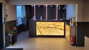 A modern reception desk with a marble top, wooden flooring, and a fire extinguisher near the door.