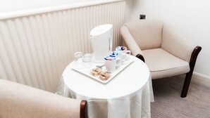 A small round table with a white tablecloth, a white pitcher, a tray with pastries, a cup, and a saucer. - Caladh Inn (Stornoway)