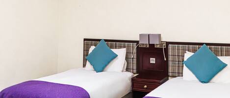 A hotel room with two beds, a skylight, a nightstand, and a wardrobe.