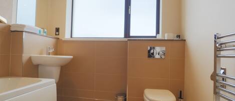 A bathroom with a sink, toilet, and a window.