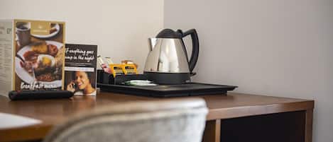 Ein Holztisch mit einem Edelstahlkessel, einer Kaffeesorte und einer Kaffeemaschine.