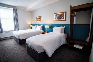 A hotel room with two beds, a large mirror, and two framed pictures on the wall.