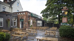 Un pub llamado "The Highfield" con mesas de madera tipo picnic al aire libre y un edificio de ladrillo.