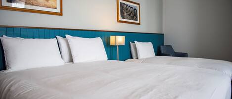 A hotel room with a large bed, two bedside tables, a lamp, and two framed pictures on the wall.