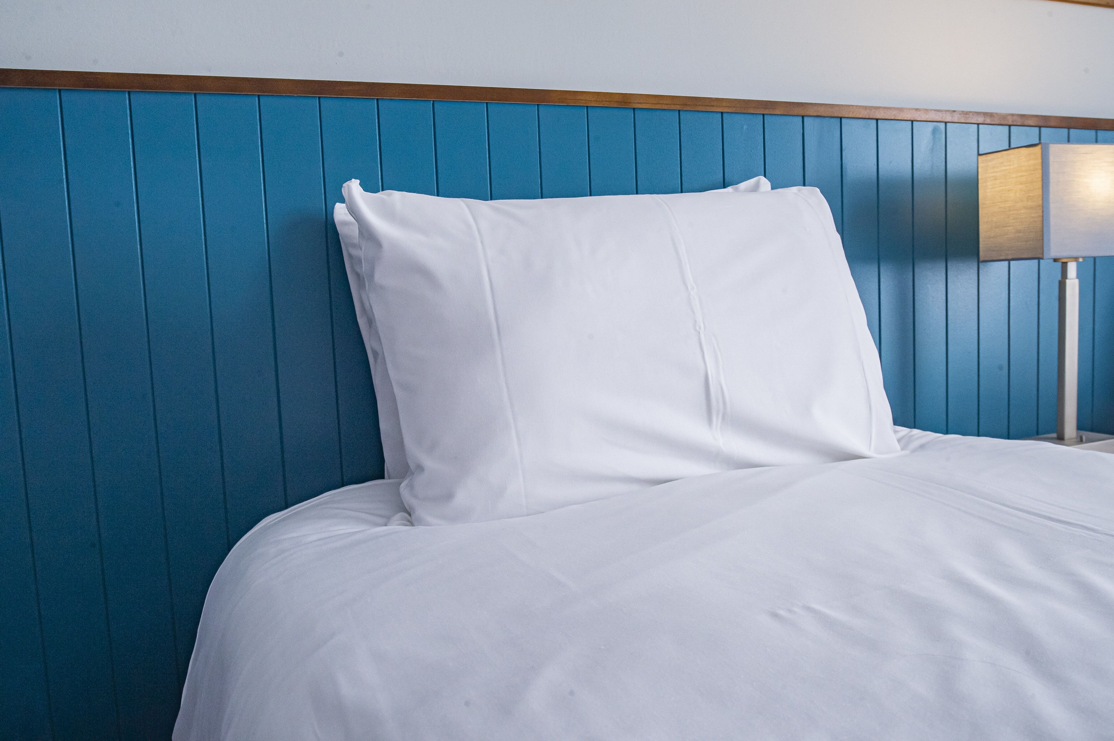 A bed with white bedding and a blue headboard.