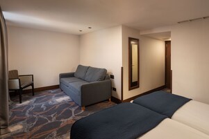 Ein Hotelzimmer mit einem Bett, einer Couch, einem Sessel und einem großen Spiegel.