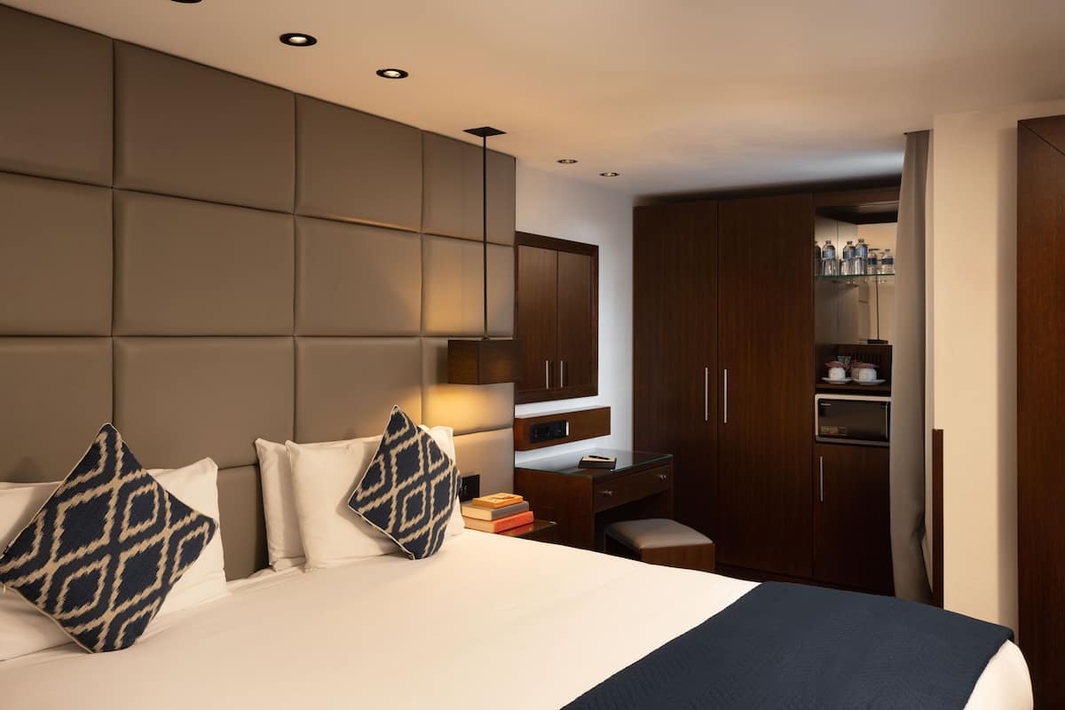 Una habitación de hotel con una cama grande, un escritorio y un armario.