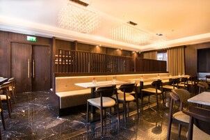 Ein modernes Restaurant mit Marmorboden, Holzvertäfelung und verschiedenen Sitzgelegenheiten, darunter Boxsitzgelegenheiten und Tische.