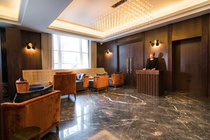 Eine Lobby mit Empfangstresen, Sitzgelegenheiten und einer Kronleuchter.