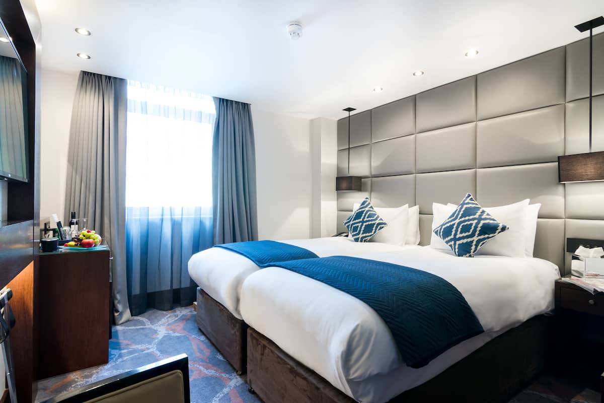 Una habitación de hotel con una cama grande, un escritorio con espejo y una ventana con cortinas.