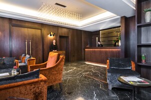 A lobby with a reception desk, plush seating, and a modern chandelier.