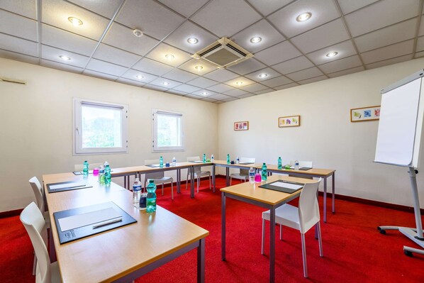 A conference room with tables, chairs, a whiteboard, and framed pictures on the wall. - Comfort Hotel Paris Porte d'Ivry (Ivry-sur-Seine)