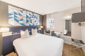 Une chambre d’hôtel avec un grand lit, un bureau, une chaise, une télévision et une vue sur la ville.