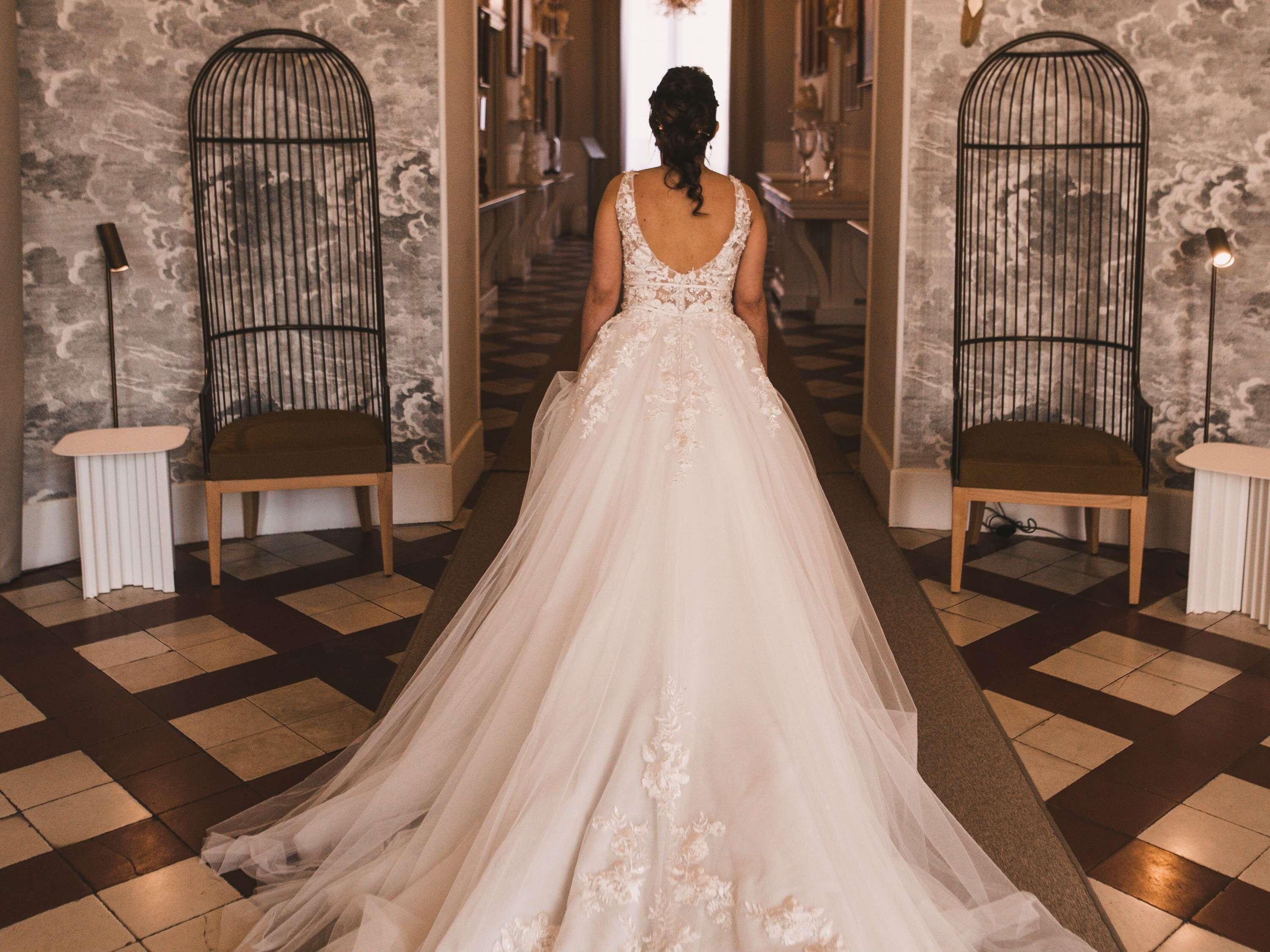 A bridal gown in a hallway with patterned walls and a checkered floor.